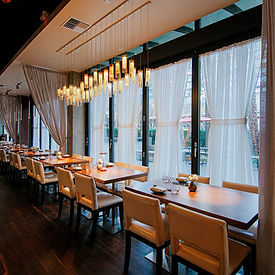 Restaurant dining room with tables and window curtains.