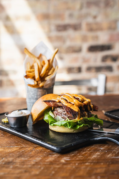 Delicious burger with fries, and a dipping sauce. Served on a wooden table. at Burgerology