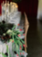 Red tulips in a table end display of fresh flowers, fruits and draping.
