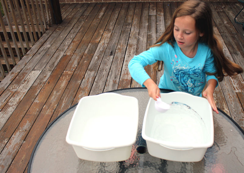 Photo of a girl doing a heart science activity by scooping water from one bin to another as fast as she can.