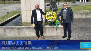 Dois homens homenageiam antigos combatentes em Vila Nova de Cerveira, segurando uma coroa de flores amarelas e brancas.