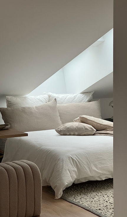 Helles Schlafzimmer im Dachgeschoss mit Oberlicht und Bettwäsche in Weißtönen, Ausbau einer Dachwohnung in München. 
