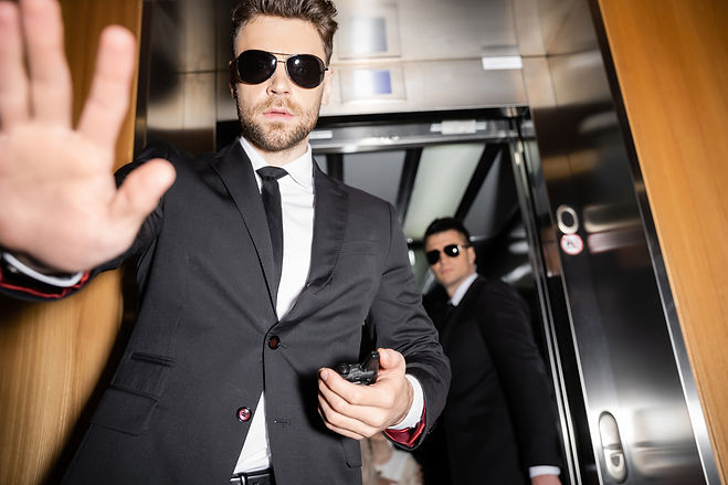 private security concept, handsome bodyguard in sunglasses and suit showing stop, no gestu