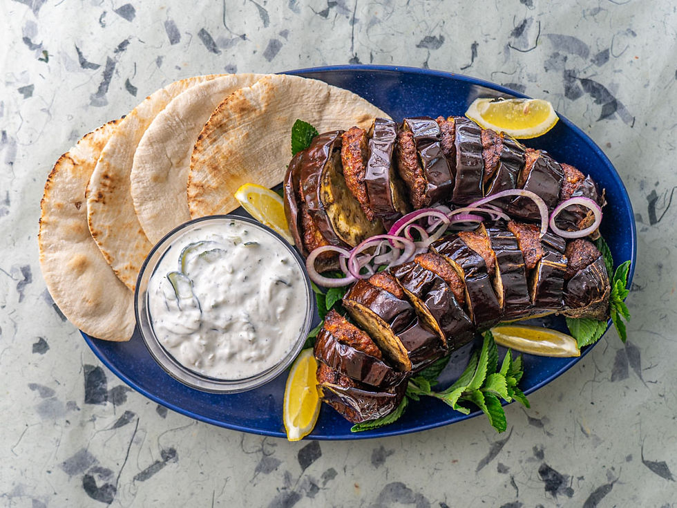 Baked eggplant stuffed with savory served with pitas and tzatziki sauce