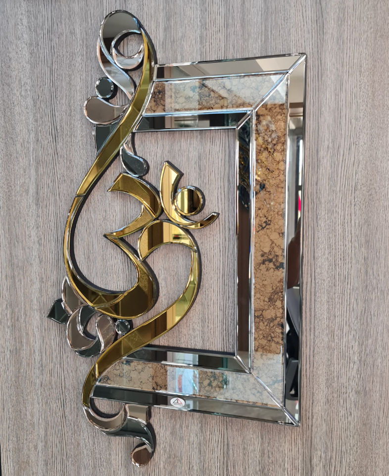 A decorative rectangular wall mirror with a wide border and an ornate, curved Om symbol overlaid on the left side. The Om is a shiny gold finish, and the frame segments are made of beveled mirrors with some sections featuring a brown texture.