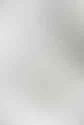 구겨진 흰 천 위에 하얀 튜브 형태의 화장품이 세워져 있다