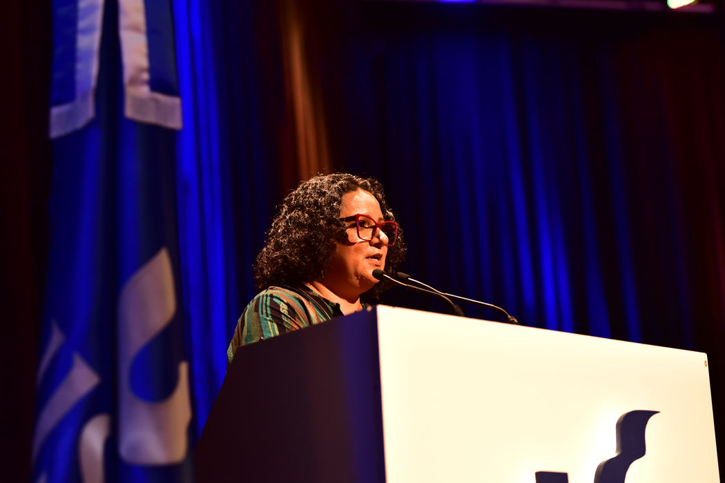 Viviane Feijó Machado, presidente do Comitesinos, falando ao público, no púlpito, no anfiteatro Padre Werner, na Unisinos.