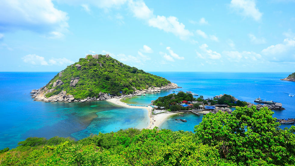 Lush green island with rocky hills surrounded by turquoise sea. Sandy beaches connect to smaller islets under a bright blue sky.