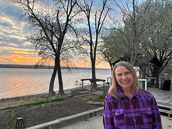 Woman standing near a river at sunset