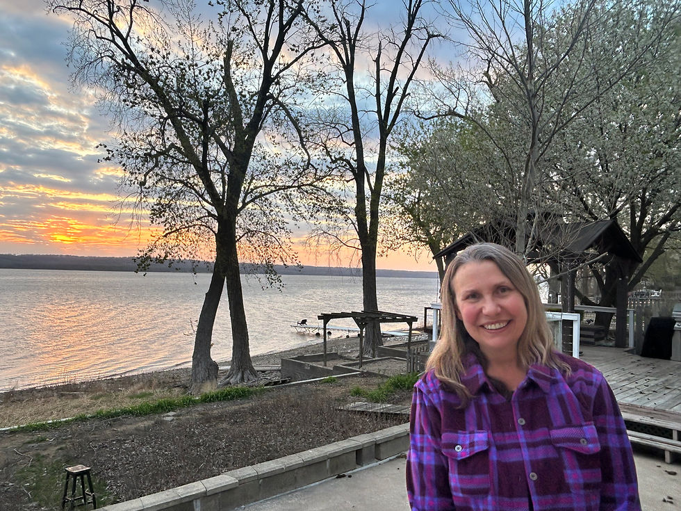 Woman standing near a river at sunset