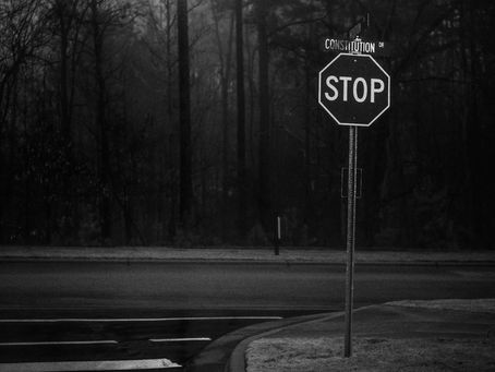 Stop sign at Constitution Drive intersection with dark forest background