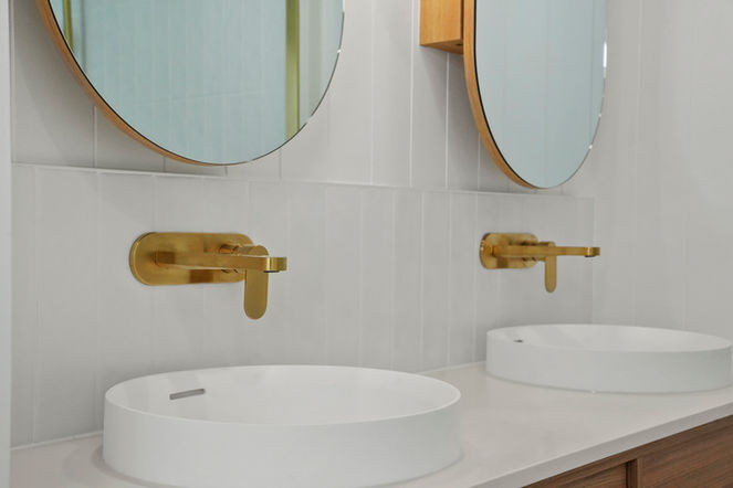 Twin vessel basins with brushed brass wall-mounted tapware and arched mirrors in a Gold Coast bathroom renovation