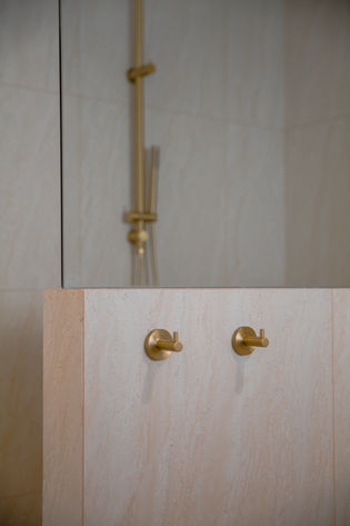 Modern bathroom renovation Gold Coast with brushed brass rainfall shower set and textured feature wall tiles