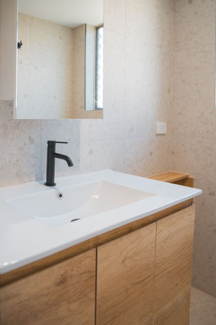 Contemporary laundry and bathroom renovation with oak vanity and terrazzo tiles.
