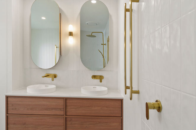 Modern coastal main bathroom renovation with a custom walnut double vanity and brushed brass tapware