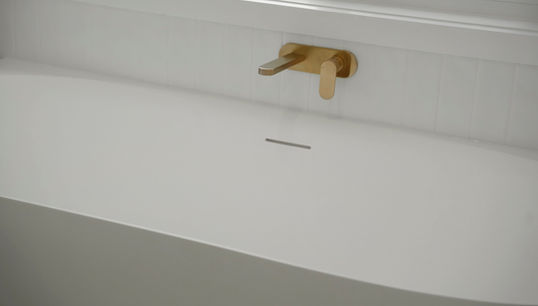 Freestanding bath with brushed brass wall-mounted bath spout in a modern coastal bathroom renovation