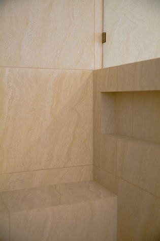 Luxury bathroom renovation Gold Coast showcasing floor-to-ceiling stone-look tiles and shower seat.