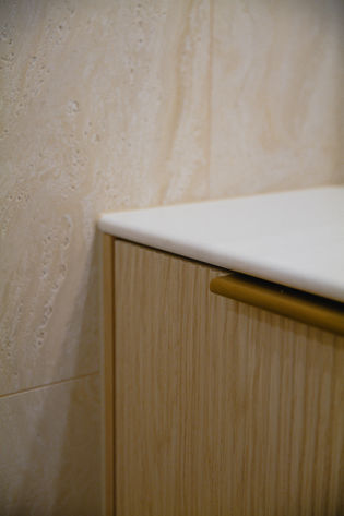Bathroom renovation Gold Coast featuring white stone benchtop, fluted timber vanity cabinetry and brushed brass handle detailing.