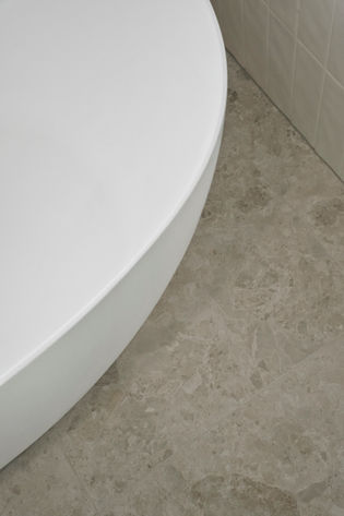 Freestanding bath with natural stone-look floor tiles in a luxury bathroom renovation.