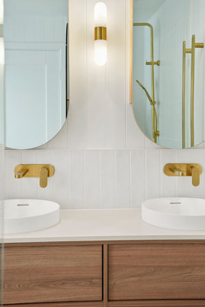 Custom walnut double vanity with vessel basins and brushed brass wall-mounted tapware