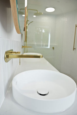 White vessel basin with brushed brass wall-mounted tapware in a bespoke bathroom renovation