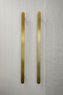 Brushed brass heated towel rails in a modern coastal bathroom design