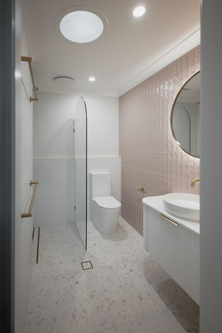 Curved frameless shower screen with brushed gold tapware in a luxury bathroom