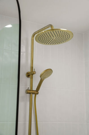 Brushed brass rainfall shower and handheld shower in a luxury bathroom renovation