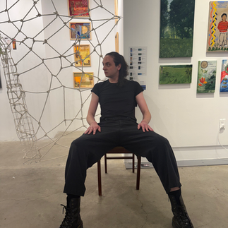 Performer seated inside a wire installation during a live performance at Clio Art Fair