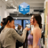 Shelly Luana doing live painting on a model during Clio Art Fair’s 23rd Edition, with visitors and artworks visible inside the Chelsea exhibition space