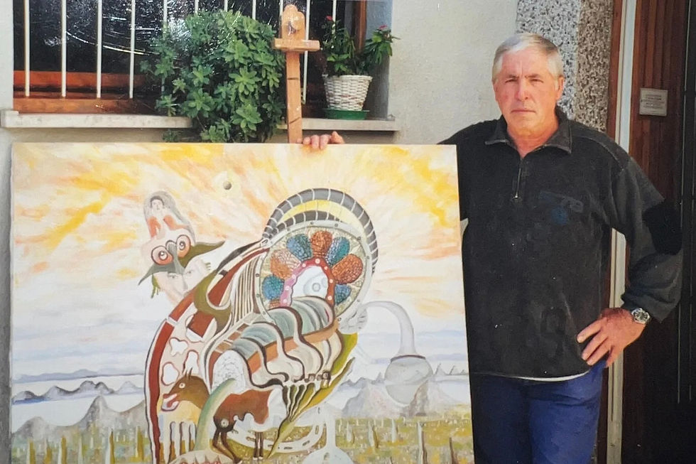 Franco Manià standing beside a colorful abstract painting with sunset colors and intricate designs, outside by a window with plants, looking serious.