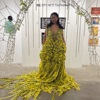 Performer wearing a large yellow sculptural costume inside a wire installation at Clio Art Fair