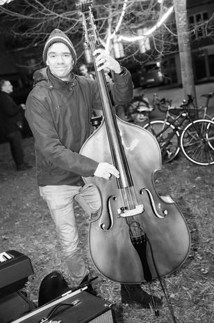 Black-and-white photo of a musician playing double bass during an outdoor concert