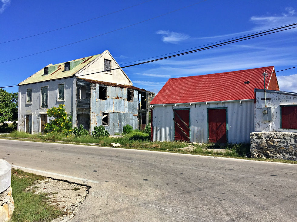 Two gray buildings on a street, the one on the right has a bright red roof and doors.