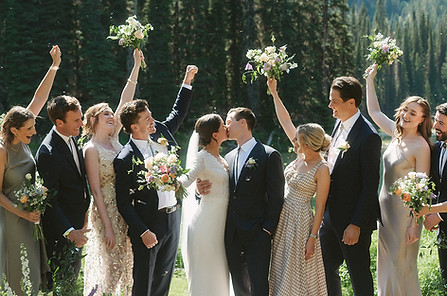 Wedding party cheering outdoors in mountain setting with bride and groom