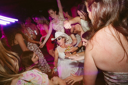 Crowded dance floor with guests dancing under colorful party lights