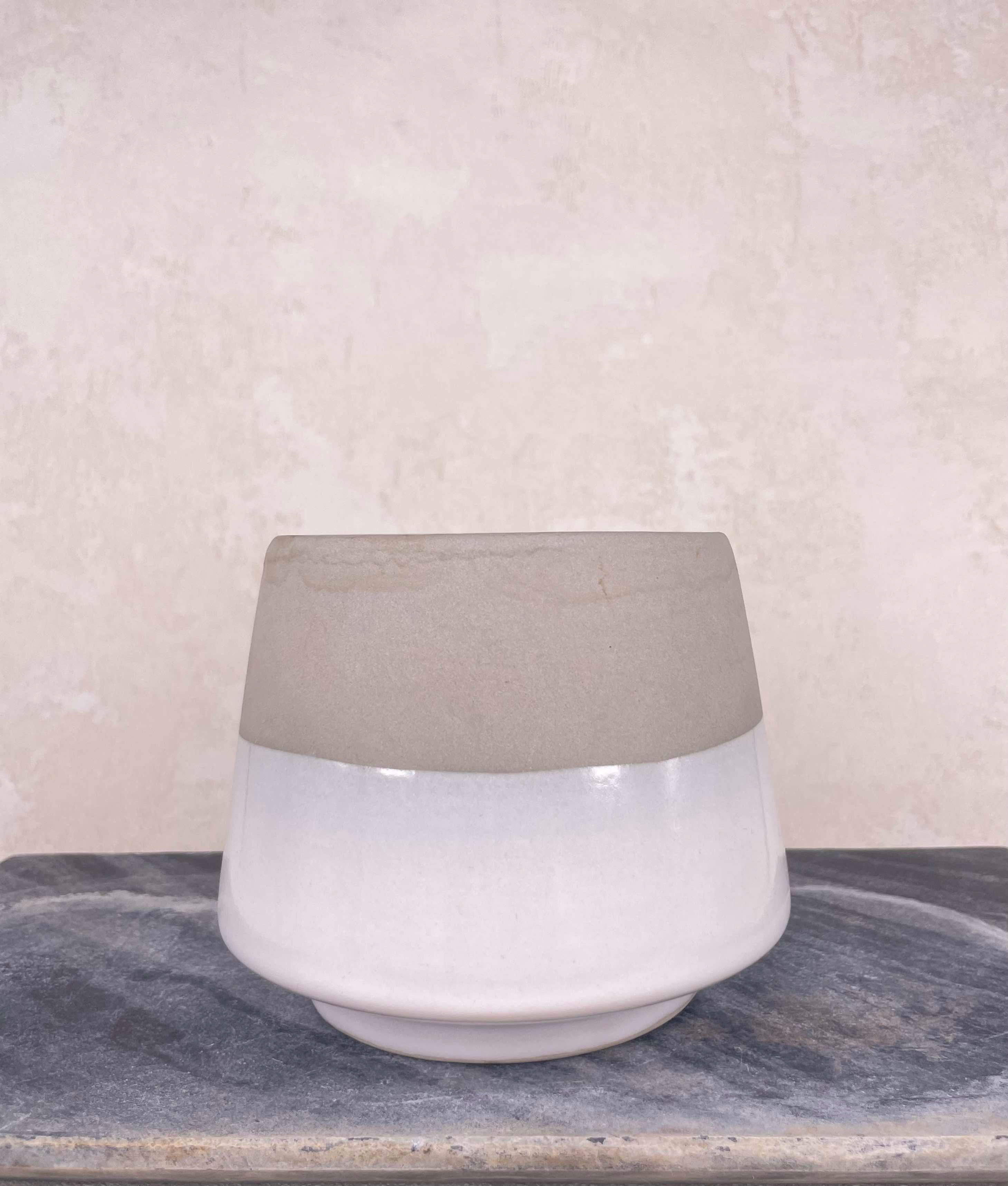 minimalistic decor, contemporary hand thrown studio pottery pot in white drip glaze bottom and earthy raw clay top. rustic.
