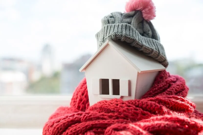 Small model house wrapped with a scarf and woolly hat