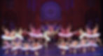 Ballet troupe in pink tutus poses on a cathedral-like stage before a purple rose window, elegant and celebratory.