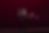 Ballet dancers lift and twirl on a dark stage, woman in burgundy dress, man in teal, against a deep red backdrop.