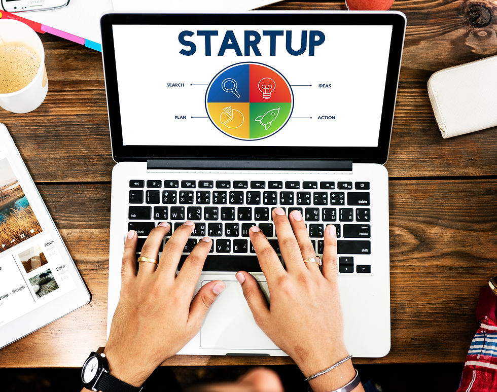 Hands typing on a laptop displaying a startup diagram with colored segments labeled Search, Ideas, Plan, Action. Wooden desk background.