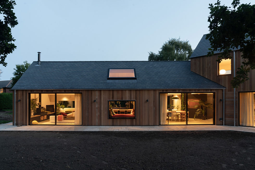 okoHaus window and door installation at Timbers, Woolverstone, at dusk, showing the lights on in the house.