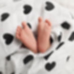 Thumbnail: Tiny baby feet poking out of the heart swaddle included in the gift box