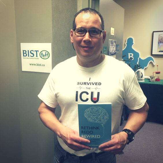 Anthony Aquan-Assee holds his book Rethink, Redo, Rewired in front of the BIST Office