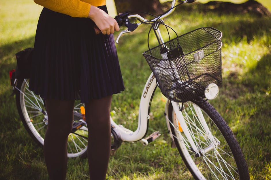 woman wearing a skirt standing with her bike