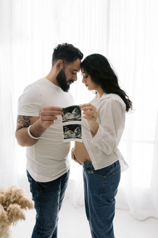 Asian parents holding up scan during maternity session