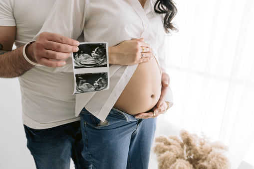 father holding scan near baby bump during maternity session