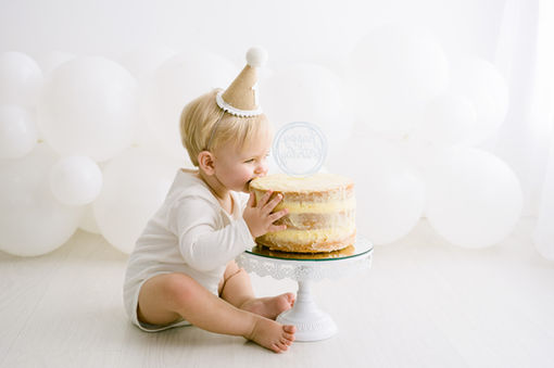 baby in party hat eating cake during first smash and splash session