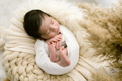 Asian baby wrapped in a basket during newborn session