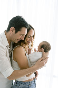 father hugging mother holding newborn during newborn session